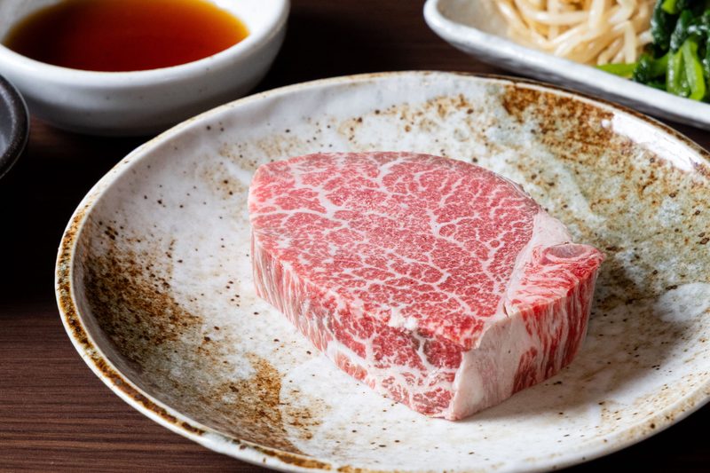 陶器の皿に盛った厚切りの赤身ステーキ肉