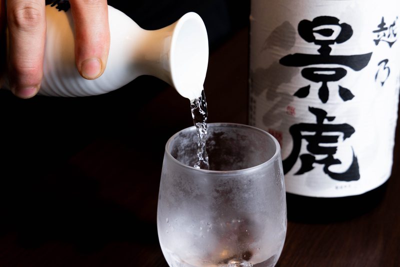 日本酒「越乃景虎」をグラスに注ぐところ