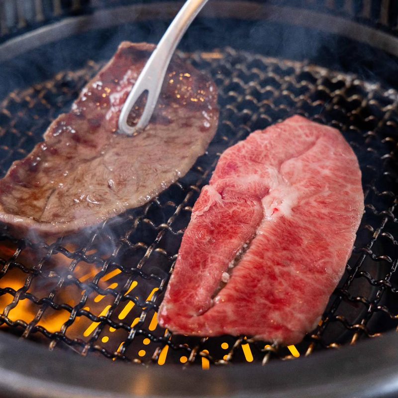 炭火の網の上で焼かれる厚切り和牛